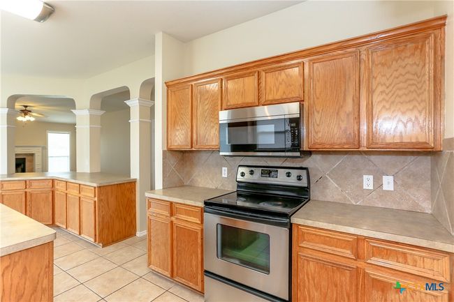 Kitchen showing the stove, microwave and tile backsplash. | Image 14