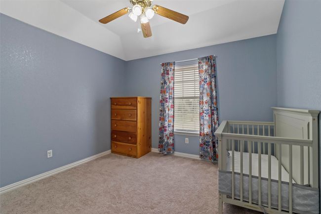 Bedroom featuring carpet, vaulted ceiling, a ceiling fan, and a crib | Image 27