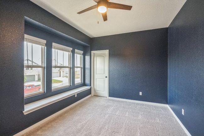 Carpeted empty room with a ceiling fan, healthy amount of natural light, a textured wall, and baseboards | Image 14