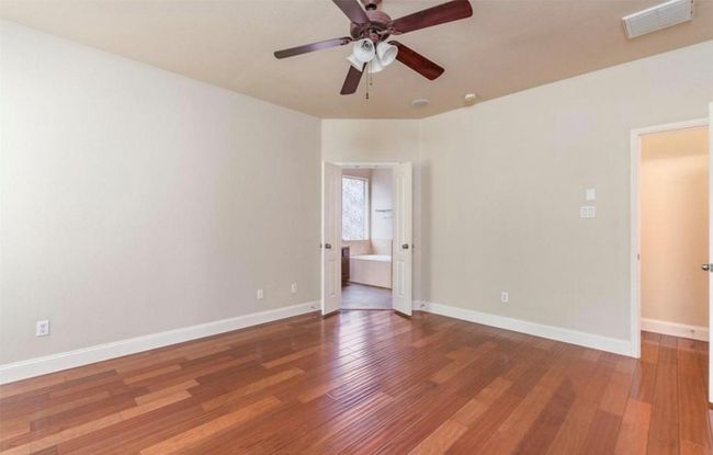 Unfurnished room with ceiling fan, wood finished floors, and baseboards | Image 14