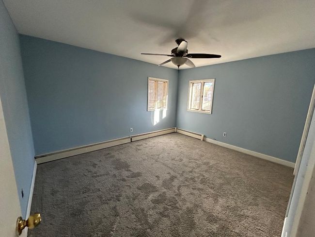 Carpeted empty room featuring baseboard heating and ceiling fan | Image 15