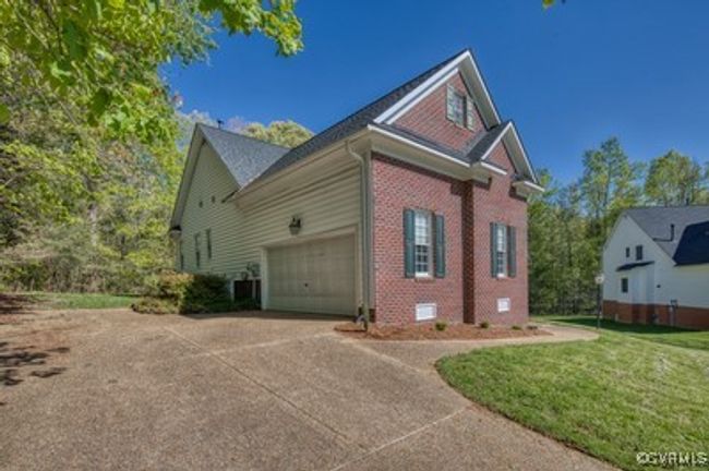 View of property exterior featuring brick siding, a yard, an attached garage, and concrete driveway | Image 31