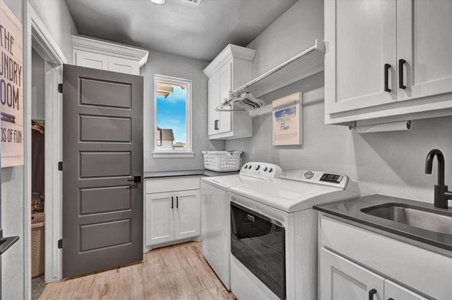 Laundry area with cabinet space, independent washer and dryer, and light wood-type flooring | Image 25