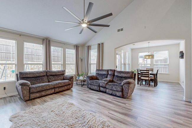 Living area with arched walkways, a ceiling fan, wood finished floors, high vaulted ceiling, and plenty of natural light | Image 27