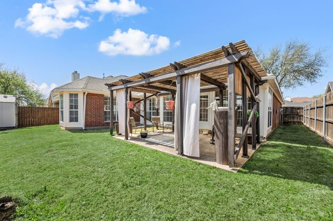 Rear view of house featuring a patio area, brick siding, a fenced backyard, a pergola, and a lawn | Image 36