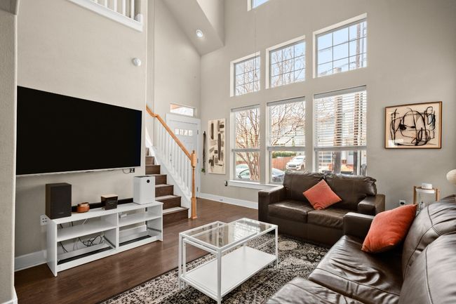 Living room with baseboards, a high ceiling, wood finished floors, and stairs | Image 4