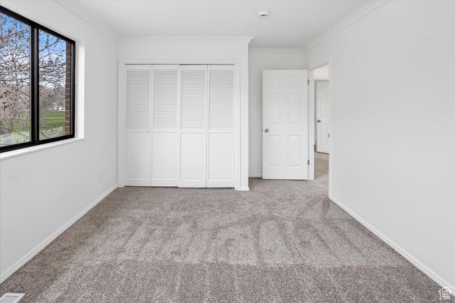 Unfurnished bedroom with baseboards, a closet, crown molding, and carpet floors | Image 26