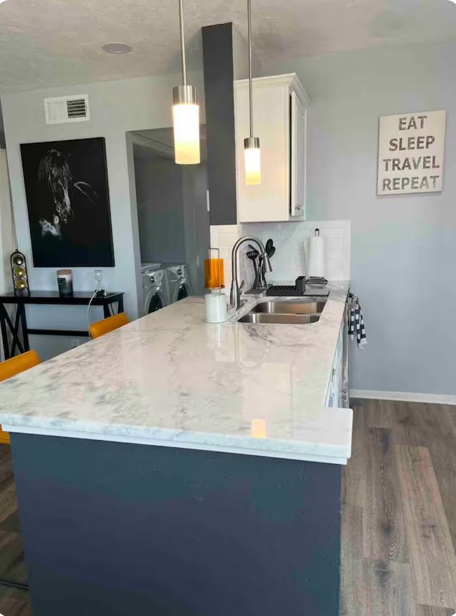 Kitchen with washing machine and clothes dryer, sink, dark hardwood / wood-style flooring, decorative light fixtures, and white cabinets | Image 7