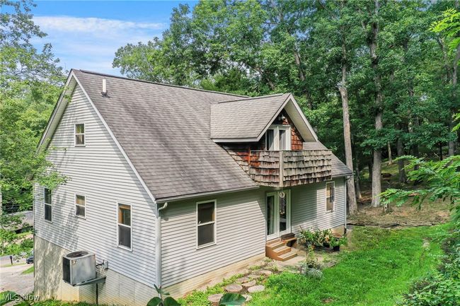 Rear view of house with view of scattered trees, entry steps, and a shingled roof | Image 46