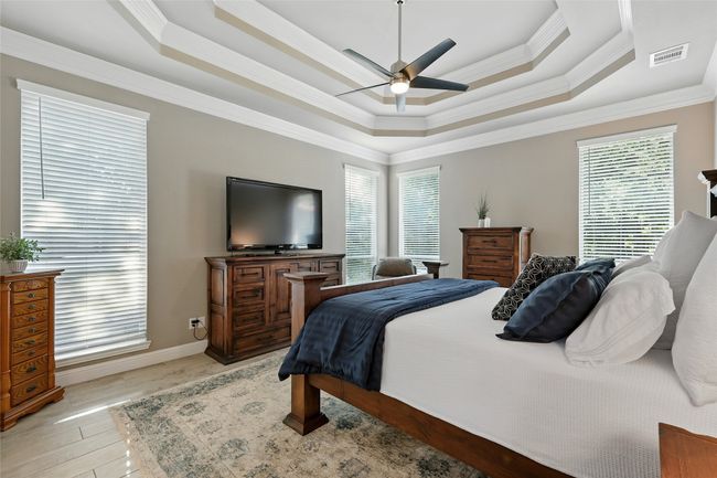 Bedroom with a raised ceiling, multiple windows, ornamental molding, a ceiling fan, and light ceramic tile wood-type flooring | Image 15