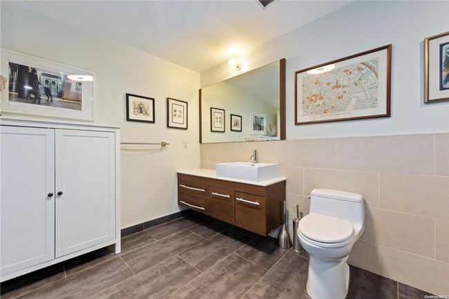 Bathroom with toilet, tile walls, and vanity | Image 9