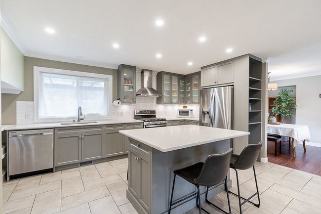 Kitchen with gray cabinetry, a sink, wall chimney exhaust hood, and appliances with stainless steel finishes | Image 7