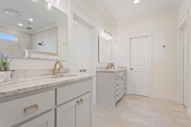 Bathroom with two vanities, a tile shower, ornamental molding, and recessed lighting | Image 20