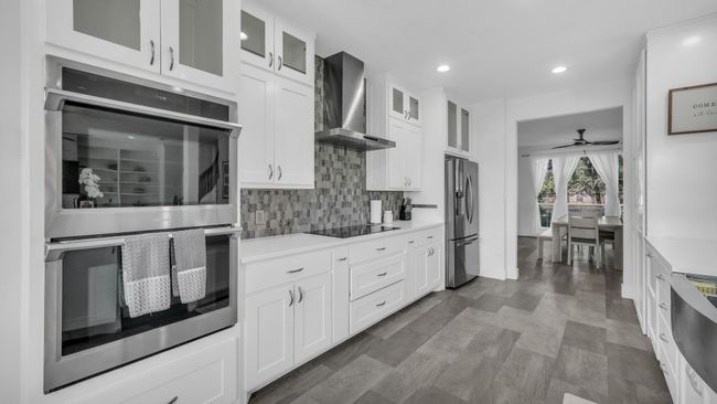 Kitchen with appliances with stainless steel finishes, wall chimney range hood, backsplash, light countertops, and recessed lighting | Image 12