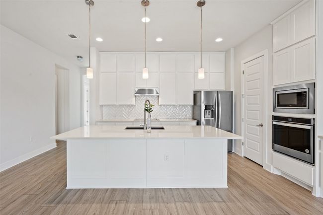 Kitchen with stainless steel appliances, tasteful backsplash, light wood-style floors, a center island with sink, and recessed lighting | Image 9