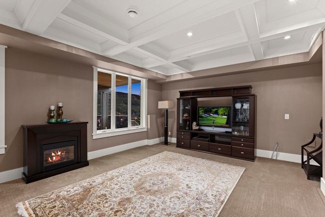 Carpeted living room with baseboards, a glass covered fireplace, coffered ceiling, and beamed ceiling | Image 33