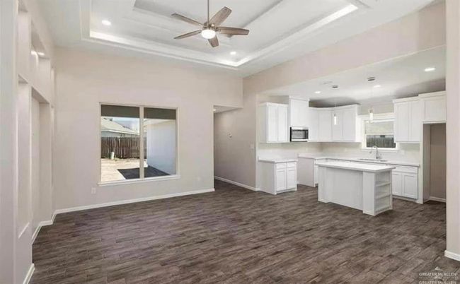 Kitchen with stainless steel microwave, dark wood-type flooring, a sink, a center island, and ceiling fan | Image 4