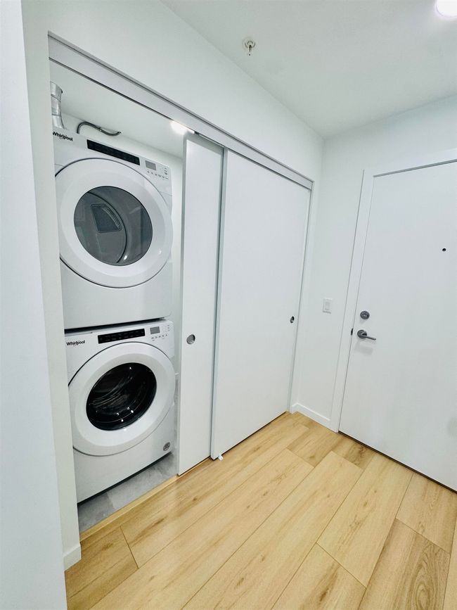 Laundry room with laundry area, stacked washer / dryer, and wood finished floors | Image 17