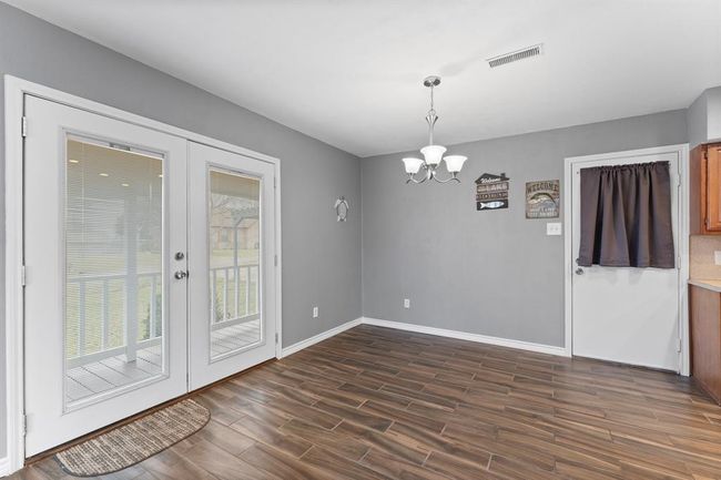 Bright dining area with modern light fixtures. Features French doors leading to a porch. | Image 13