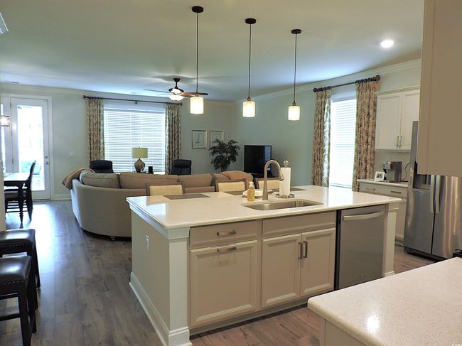 Kitchen featuring a sink, stainless steel appliances, ornamental molding, a center island with sink, and a ceiling fan | Image 4