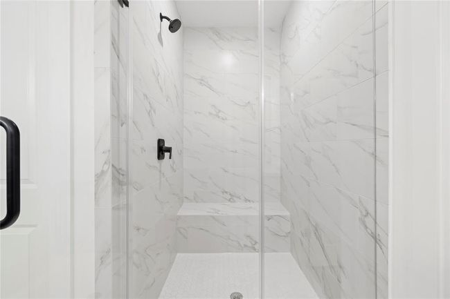 Featuring floor-to-ceiling marble-inspired tile, a sleek glass enclosure, and modern matte black fixtures for a spa-like experience. | Image 21