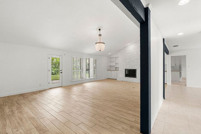 Unfurnished living room featuring recessed lighting, light wood-style floors, lofted ceiling, and a fireplace | Image 6