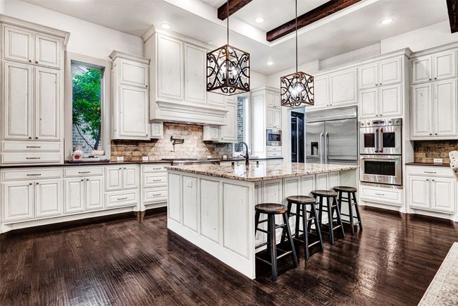 Your jaw may drop in awe when you see this amazing gourmet kitchen! Warm oak floors, granite counters on the island, leathered marble elsewhere, not to mention the professional GE Monogram appliances! | Image 5