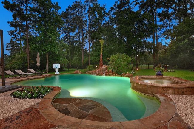 Resort-style backyard features a stunning pool and a rock waterfall, surrounded by scenic views sand lush landscaping. | Image 38