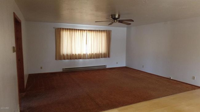 Carpeted living room featuring baseboard heating and a ceiling fan | Image 23