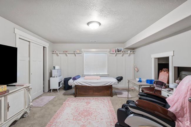 Bedroom featuring light carpet, a textured ceiling, and a closet | Image 24