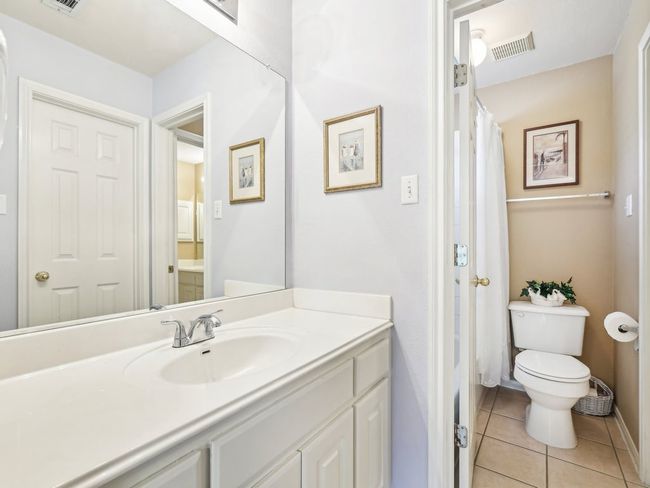 Full bath with toilet, tile patterned floors, vanity, a shower with curtain, and baseboards | Image 26