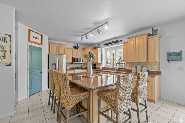 Kitchen with light brown cabinetry, appliances with stainless steel finishes, decorative backsplash, and light tile patterned floors | Image 14