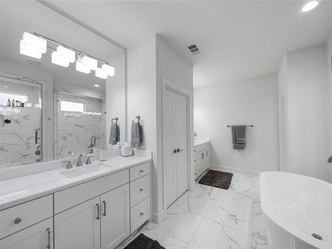 Bathroom featuring two vanities, a marble finish shower, a freestanding tub, marble look tile flooring, and recessed lighting | Image 25