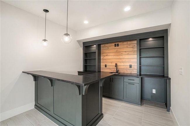 Bar featuring baseboards, light tile patterned floors, and decorative light fixtures | Image 26