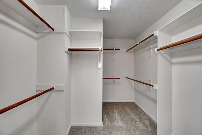Spacious walk-in closet with ample shelving and hanging space, featuring clean white walls and carpeted flooring. Ideal for organized storage. | Image 36