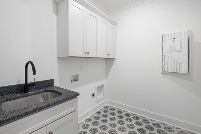 Laundry room is right by the back door and features cabinets for storage and a utility sink | Image 11