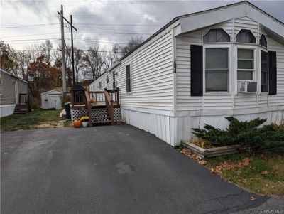 View of side of home with cooling unit, a storage shed, and a wooden deck | Image 1