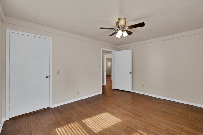 Another view of the back bedroom with a ceiling fan, and original hardwood finished floors | Image 21