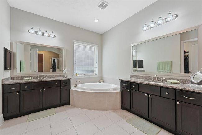 Elegant primary bathroom featuring dual vanities with granite countertops, a large soaking tub, and a separate walk-in shower. Thoughtfully designed with ample storage and natural light, creating a serene and functional retreat. | Image 17