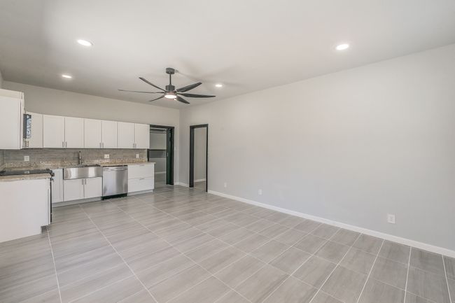 Kitchen featuring white cabinetry, stainless steel dishwasher, backsplash, a sink, and ceiling fan | Image 5