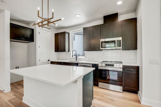 Kitchen with stainless steel appliances, a sink, light wood-style floors, a chandelier, and recessed lighting | Image 6