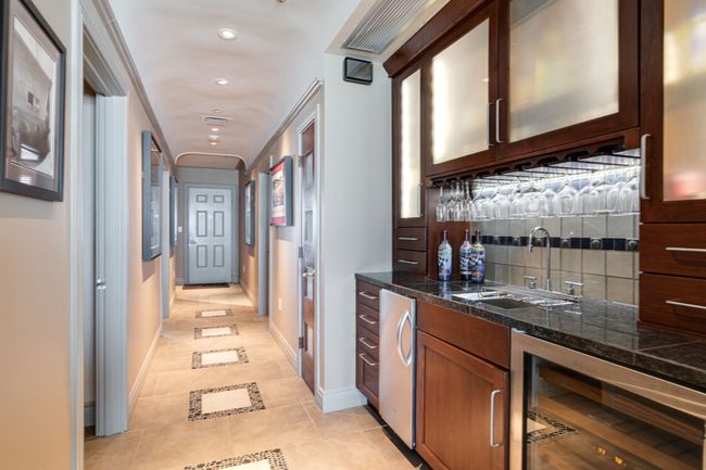 Wet bar area with lighted built ins and ice maker along with small refrigerator. | Image 14
