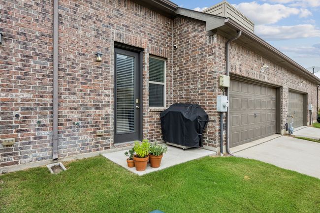 View of property exterior with brick, patio, driveway, a garage, and a lawn | Image 25