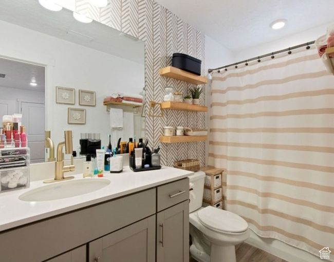 Bathroom with vanity, toilet, curtained shower, wood finished floors, and wallpapered walls | Image 14