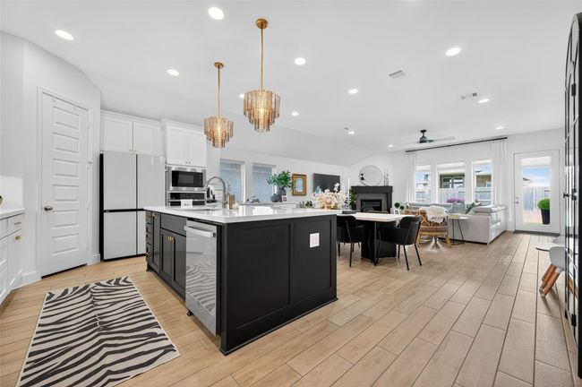 Modern kitchen featuring a large center island with undermount sink, beautiful white countertops, and sleek two-tone cabinetry. Recessed lighting provide excellent illumination throughout the open space. | Image 10
