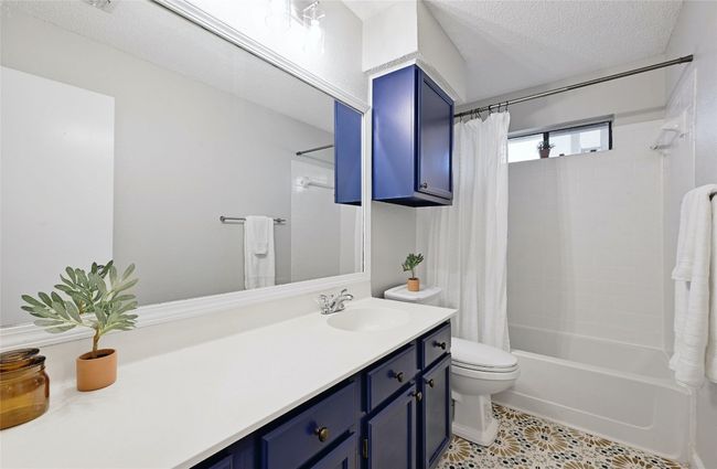 This adorably updated full bathroom is accessed from the hallway between the two secondary bedrooms and/or easy access from the kitchen/living area when entertaining. Note the upgraded mosaic floor tiles and fun-loving colored cabinetry. | Image 21