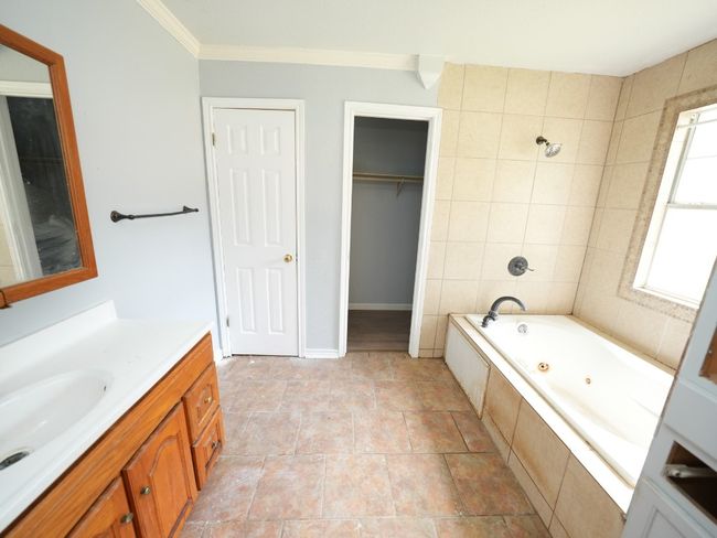Bathroom with a tub with jets, vanity, and ornamental molding | Image 17