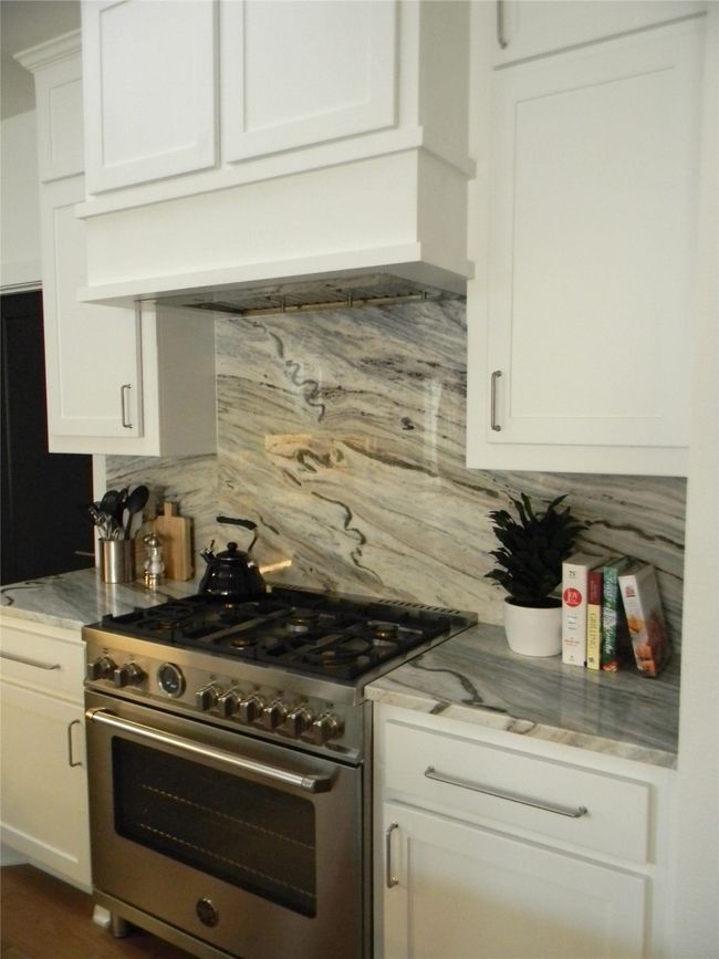 Kitchen with stainless steel gas range, stone backsplash and white cabinetry | Image 8