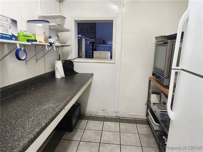 Prep room adjoining storage room with pass through window to main serving area. | Image 19
