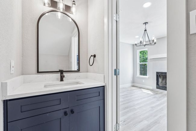 Bathroom featuring a chandelier, vanity, a glass covered fireplace, wood finished floors, and baseboards | Image 16